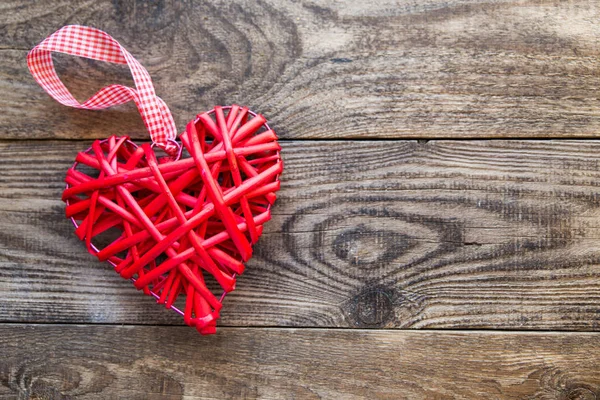 Червоне плетене серце на дерев'яному фоні — стокове фото