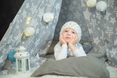 bir çocuk beyaz elbiseli bir çadırda oturur