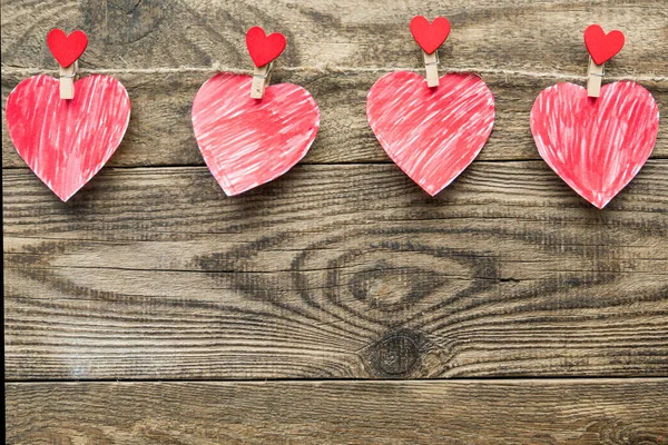 Veelkleurige harten met inscripties aan een touw op een houten achtergrond — Stockfoto