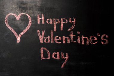 Kırmızı tebeşir kelime mutlu Sevgililer gününde siyah bir arka plan ile çizilmiş kalp