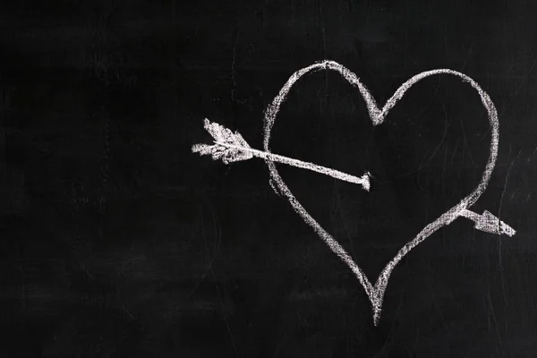 white chalk painted heart with an arrow on a black slate
