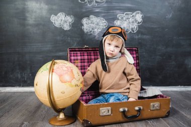 bir bavul küre içinde oturan çocuk pilot