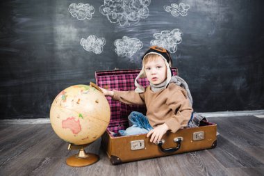 bir bavul küre içinde oturan çocuk pilot