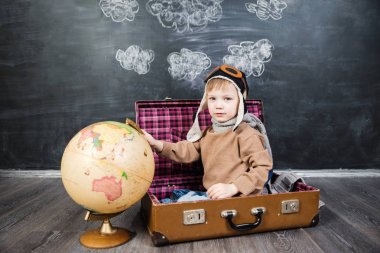 bir bavul küre içinde oturan çocuk pilot