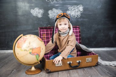 bir bavul küre içinde oturan çocuk pilot