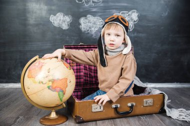 bir bavul küre içinde oturan çocuk pilot