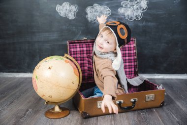 bir bavul küre içinde oturan çocuk pilot