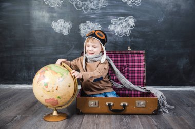 bir bavul küre içinde oturan çocuk pilot