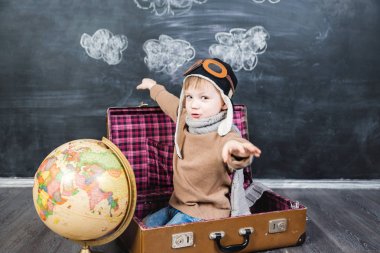 bir bavul küre içinde oturan çocuk pilot