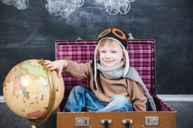 bir bavul küre içinde oturan çocuk pilot