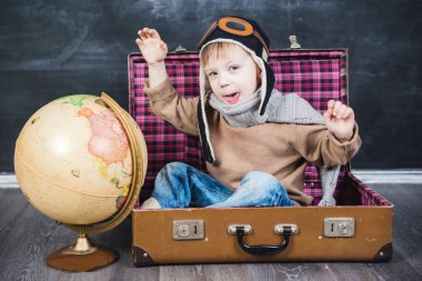 bir bavul küre içinde oturan çocuk pilot