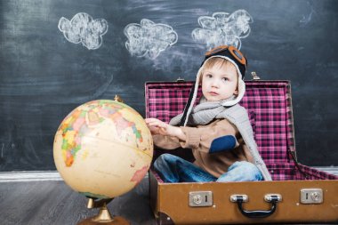 bir bavul küre içinde oturan çocuk pilot