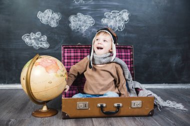 bir bavul küre içinde oturan çocuk pilot