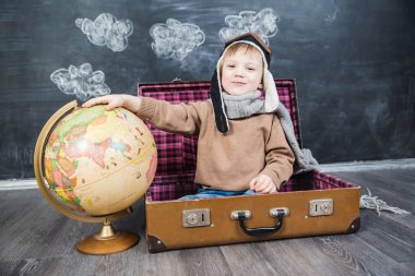 bir bavul küre içinde oturan çocuk pilot