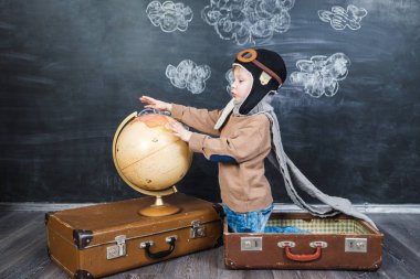 bir bavul küre içinde oturan çocuk pilot