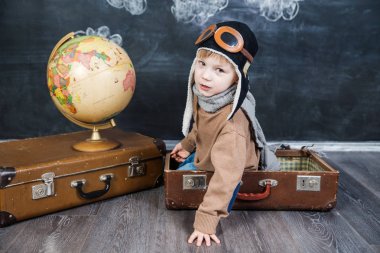 bir bavul küre içinde oturan çocuk pilot