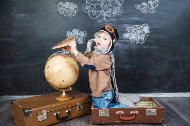 bir bavul küre içinde oturan çocuk pilot