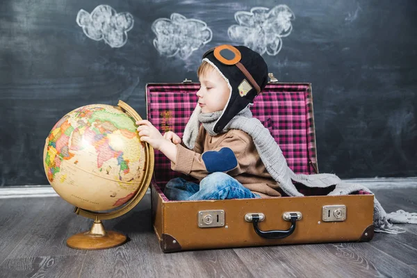 bir bavul küre içinde oturan çocuk pilot