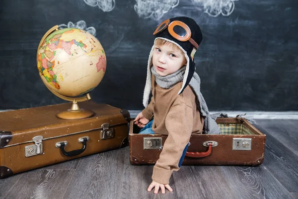 bir bavul küre içinde oturan çocuk pilot