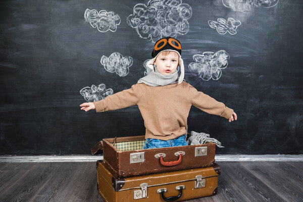 the boy in the pilot 's cap plays a paper plane
