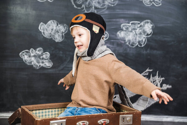 the boy in the pilot 's cap plays a paper plane
