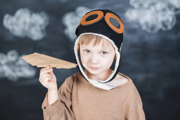 Le garçon dans la casquette du pilote joue un avion en papier — Photo
