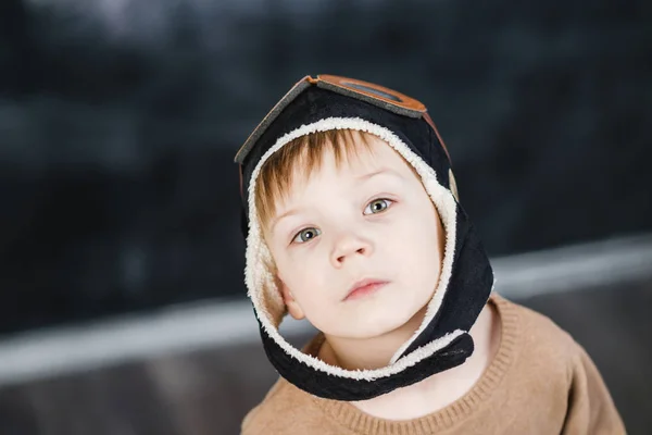 Le garçon dans la casquette du pilote joue un avion en papier — Photo