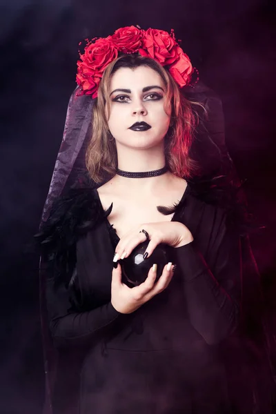 Bruxa menina em uma grinalda de rosas vermelhas — Fotografia de Stock