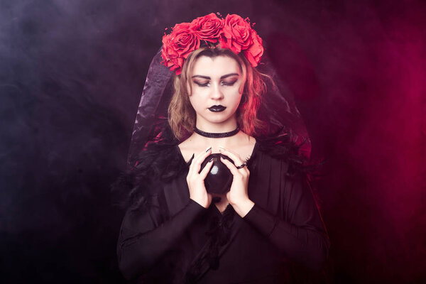 Girl witch vampire in a wreath of red roses and a black dress