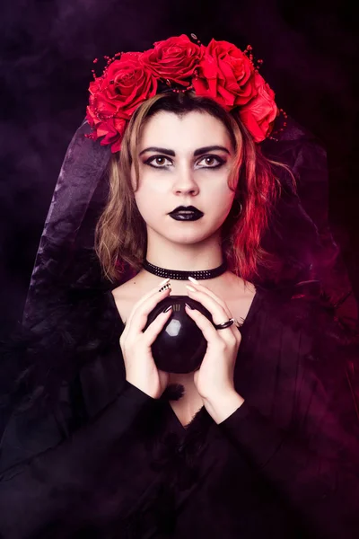 Chica bruja en una corona de rosas rojas Fotos de stock
