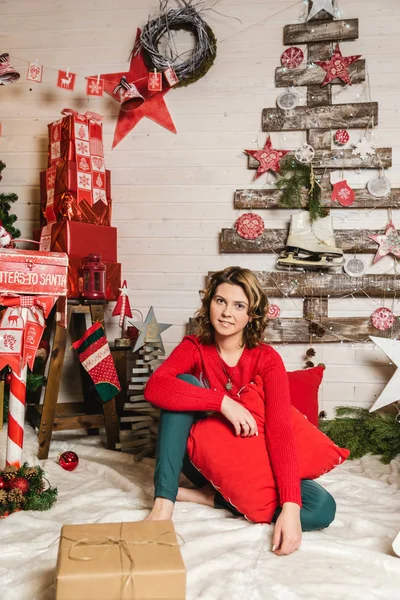 Ein Mädchen im roten Pullover mit einem Hirsch auf dem Hintergrund der Weihnachtsdekoration — Stockfoto