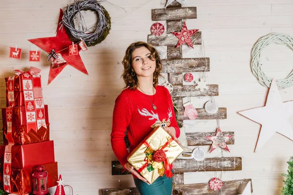 Das Mädchen im roten Pullover mit einem Rentier als Weihnachtsgeschenk — Stockfoto
