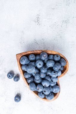 Tahta bir kasede, kalp şeklinde antioksidan yaban mersini yemek.
