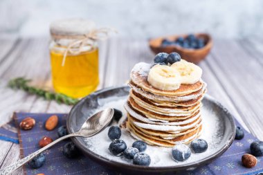 Kır kahvaltısı krepleri siyah bir tabakta yaban mersini ve bal ile