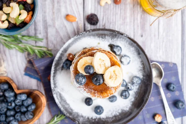 Rustiek ontbijt pannenkoeken op een donker bord met bosbessen en honing Stockfoto