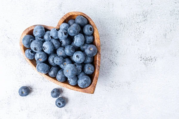 Comer arándanos antioxidantes saludables en un tazón de madera vista superior en forma de corazón Imágenes de stock libres de derechos