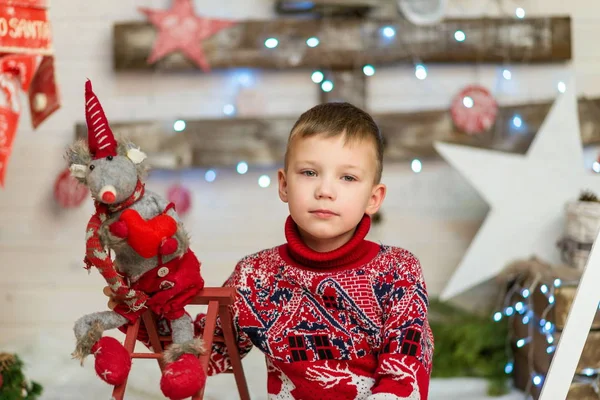 Chłopiec w czerwonym swetrze świątecznym z miękkim symbolem myszy zabawki roku — Zdjęcie stockowe