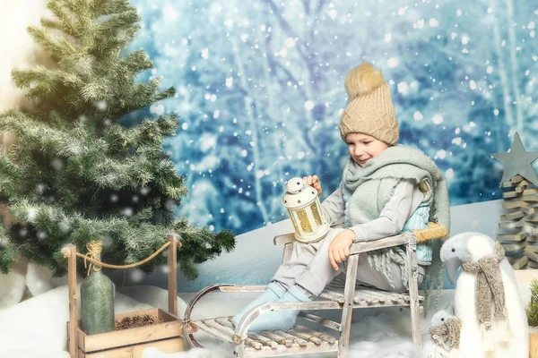 Un niño con ropa de invierno con una linterna sentada en un trineo —  Fotos de Stock