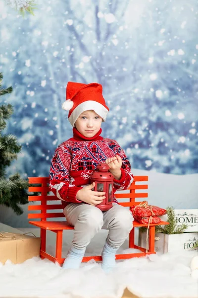 Mały chłopiec w świątecznym kapeluszu i czerwony sweter z latarnią. — Zdjęcie stockowe