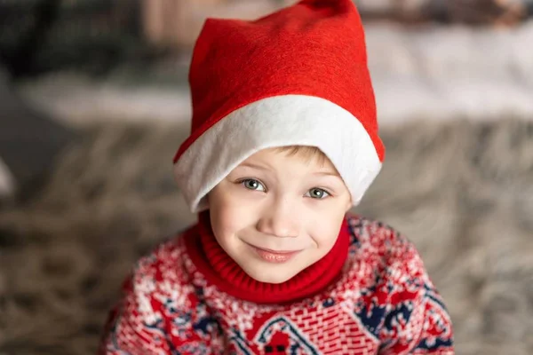크리스마스 모자를 쓰고 빨간 스웨터를 입은 소년의 사진 — 스톡 사진