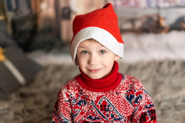 Retrato de un niño pequeño con sombrero de Navidad y suéter rojo — Foto de Stock