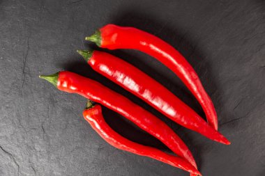 Kırmızı biberler siyah doğrama tahtasında