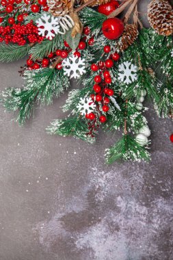 Kırmızı böğürtlenli Noel dalları ve koyu arkaplanda kar taneleri