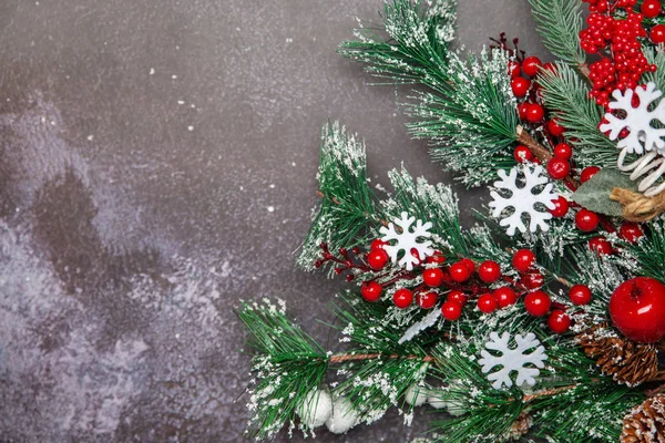 Ramoscelli di abete di Natale con bacche rosse e fiocchi di neve su sfondo scuro — Foto Stock