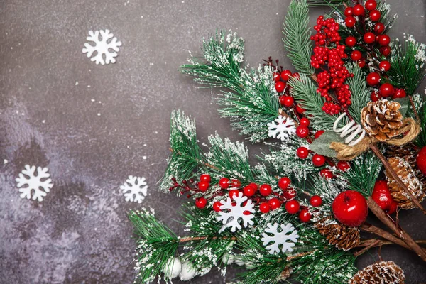 Ramoscelli di abete di Natale con bacche rosse e fiocchi di neve su sfondo scuro — Foto Stock