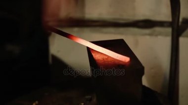 Smith çekiç üzerinde metal bir parça atıyor.