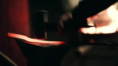 Smith çekiç üzerinde metal bir parça atıyor.