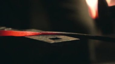 Smith çekiç üzerinde metal bir parça atıyor.