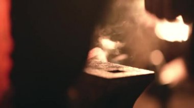 Smith çekiç üzerinde metal bir parça atıyor.