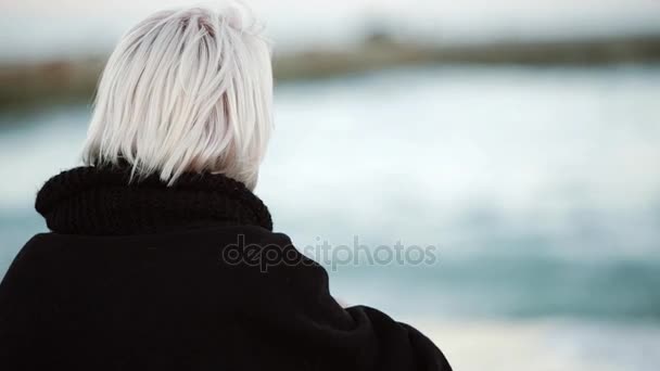 Στην παραλία, πίνει καφέ. Αυτός φαίνεται στην απόσταση, ισιώνει τα μαλλιά του. Θέα από το πίσω μέρος — Αρχείο Βίντεο